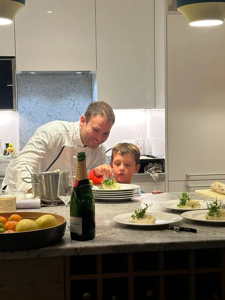 A child helps plate dishes alongside the private chef