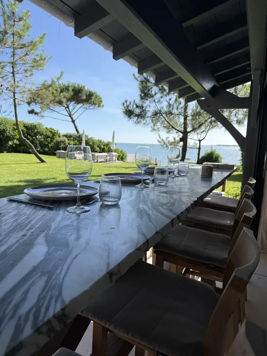 Summer table set on a terrace opening onto a villa garden