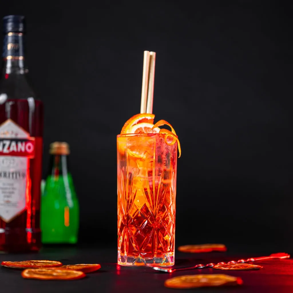 Cocktail orangé servi au bar, bouteilles en arrière-plan