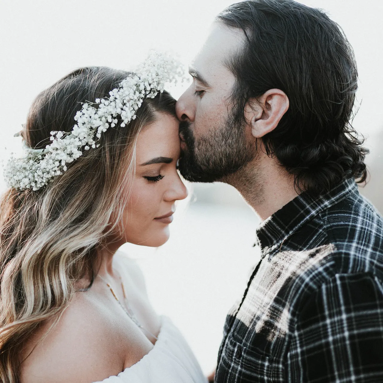 La mariée, couronne de fleurs dans les cheveux, embrassée sur le front