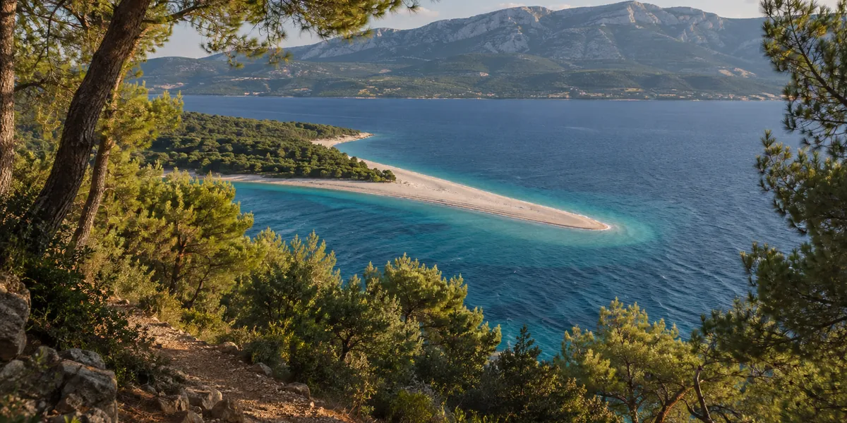 Zlatni Rat beach on the island of Brač, a white pebble spit in turquoise water seen from the pine forest